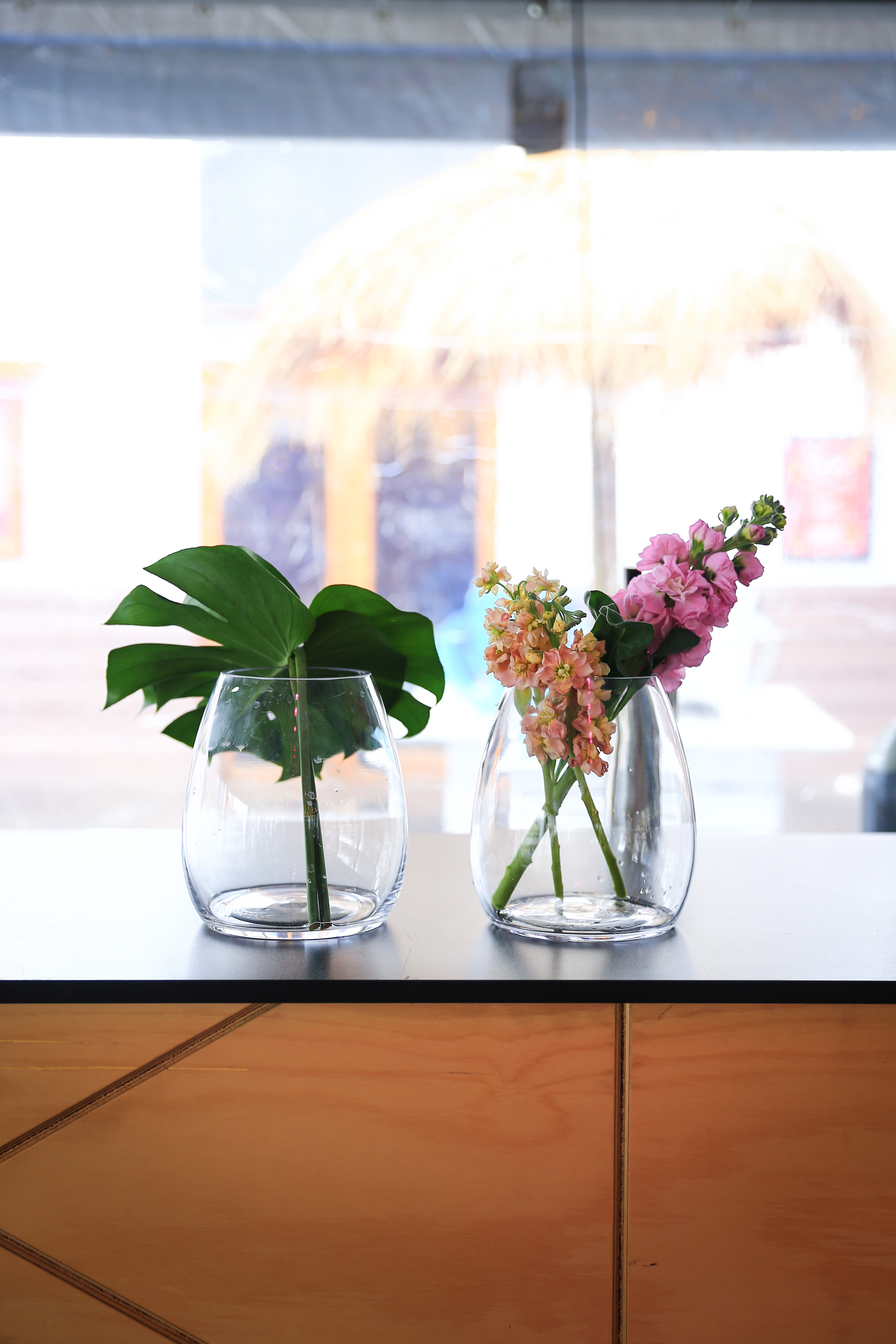 Fresh flowers in clear vases near soft window light.